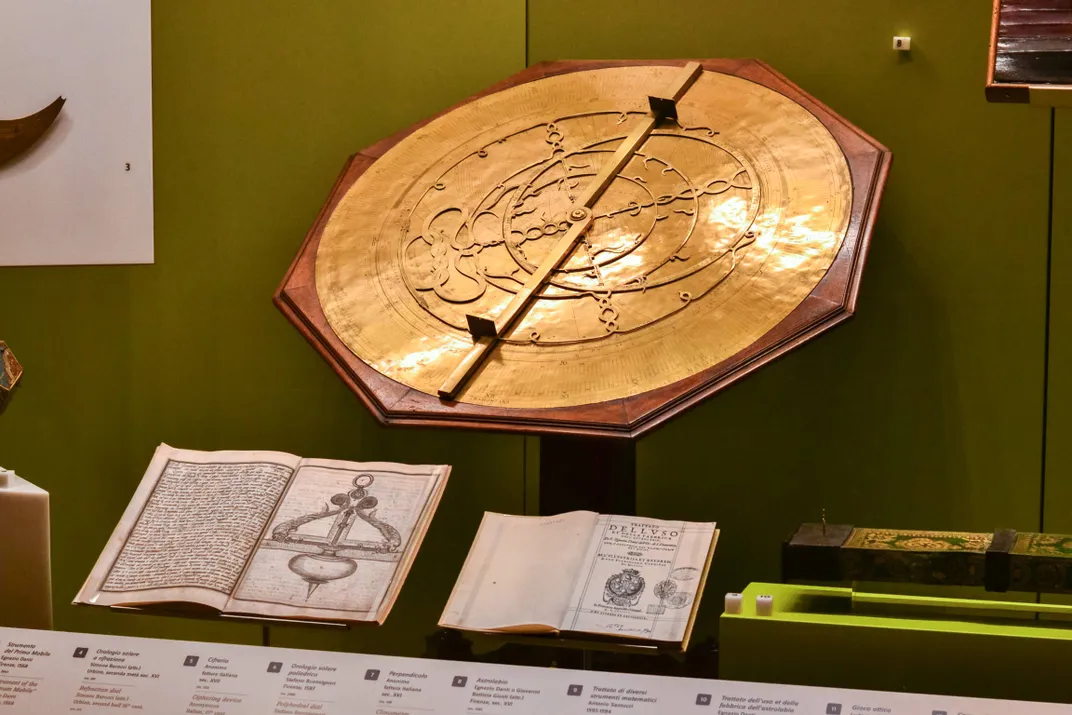 In einer Museumsvitrine steht ein goldenes Astrolabium auf einem geneigten Tisch
