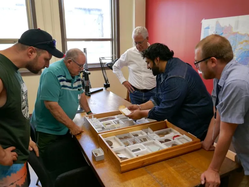 Fünf Personen stehen um einen Tisch mit Fossilien in einer Kiste