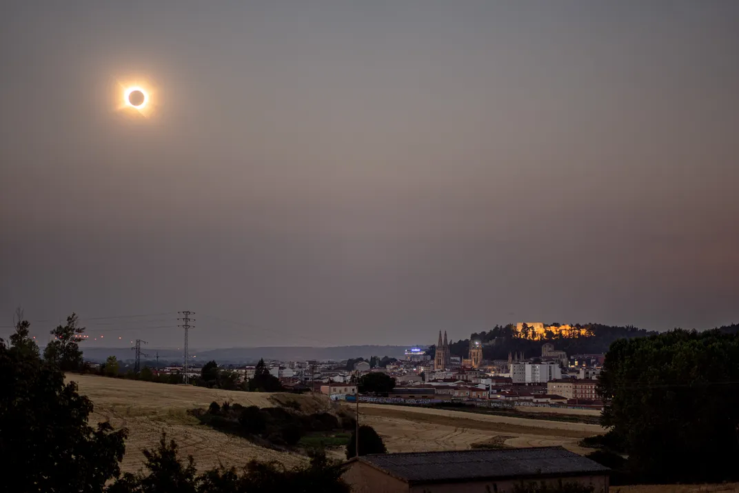 eine verfinsterte Sonne am Himmel über Telefonleitungen und Gebäuden