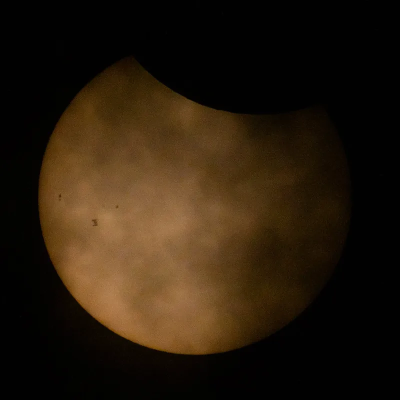Ein Raumschiff bewegt sich über die Oberfläche der teilweise verfinsterten Sonne, in Richtung der linken Seite der Sonnenfläche