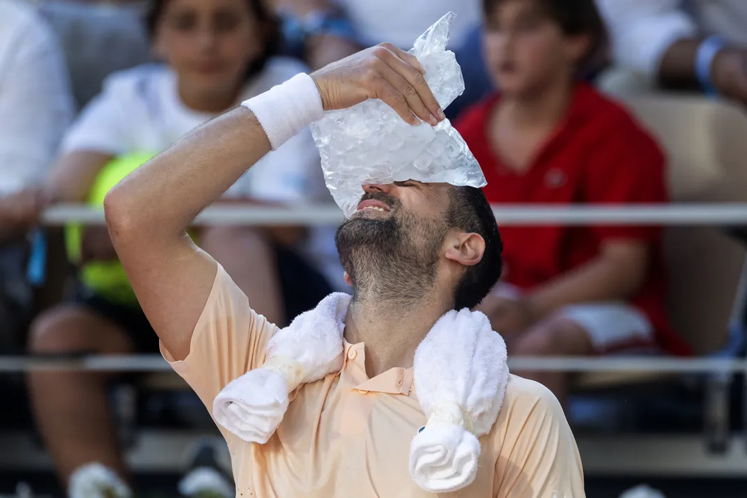 Ein Tennisspieler lehnt den Kopf zurück und hält sich einen Beutel Eis an die Stirn